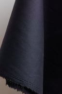 Gros plan sur les plis profonds du tissu coton déperlant anthracite, texture mate et légèrement enduite.
