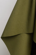 Gros plan sur les plis profonds du tissu coton déperlant vert kaki, texture mate et légèrement enduite.