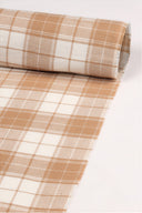 Gros plan sur le coin du tissu Le Carreau 008 écru à carreaux caramel façon vichy, mettant en valeur le motif et la lisière effilochée.