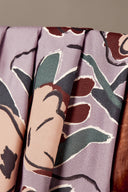 Tissu viscose Peony lavande à imprimé floral graphique de pivoines terracotta et vert sapin, drapé sur l'accoudoir en bois d'une chaise vintage.