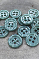 Close-up of the same small four-hole round buttons, highlighting the shine of the material.