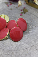 Même série de boutons Gem terracotta facettés à liseré doré, vue sous un angle rapproché différent, laissant apparaître l'anneau de couture doré à l'arrière d'un bouton.
