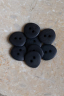 Les boutons vus de dessus, empilés au centre d'une pierre beige marbrée.