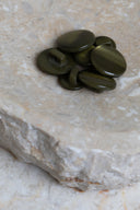 Les boutons vus de dessus, empilés au centre d'une pierre beige marbrée.