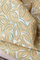 Gros plan sur les plis du tissu Petal moutarde à motif de feuilles graphiques sauge.