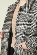 Patron Le Manteau – Plan buste, manteau pied-de-poule noir/blanc ouvert, pull camel, main en poche – Atelier Brunette