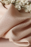 Tissu dobby rose blush froissé, posé à côté de fleurs séchées blanches (achillée), vue rapprochée de la texture.