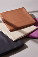 Quatre coupons de double gaze Flake pliés côte à côte dans plusieurs coloris (anthracite, écru, caramel, fuchsia), montrant la gamme de couleurs.