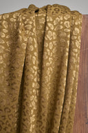Tissu jacquard Leony kaki doré à motif léopard tissé en relief, drapé en plis contre un support en bois.