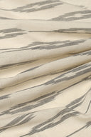 L'Ikat fabric in off-white with anthracite ikat-style stripes, draped in diagonal folds.